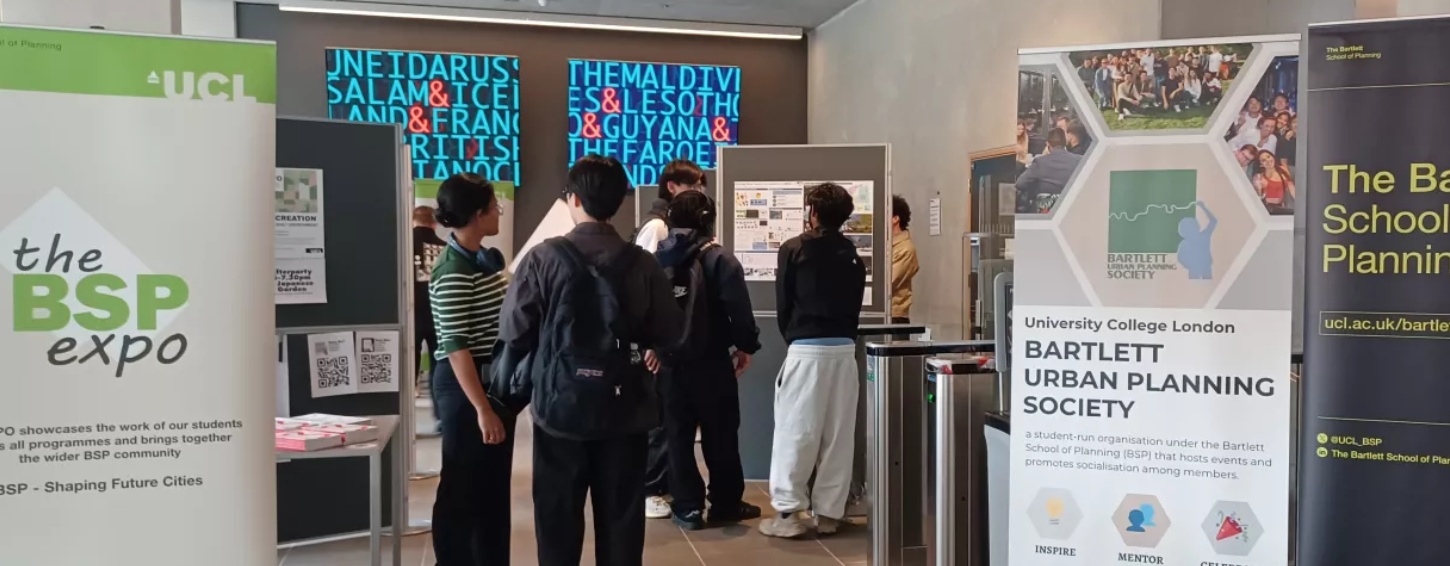 Photo of students standing around chatting and talking about exhibits at a UCL Bartlett Urban Planning Society event.