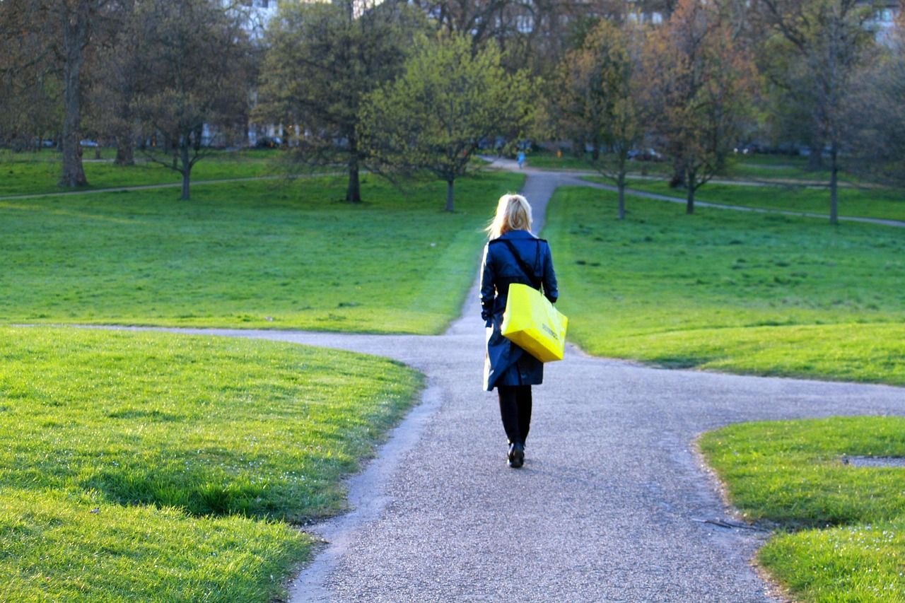 Image of woman walking away from the camera down a path through park land. Source: Image by GreenCardShow from Pixabay