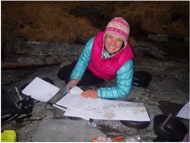 Adventurer Justine Curgenven studying maps in a cave.