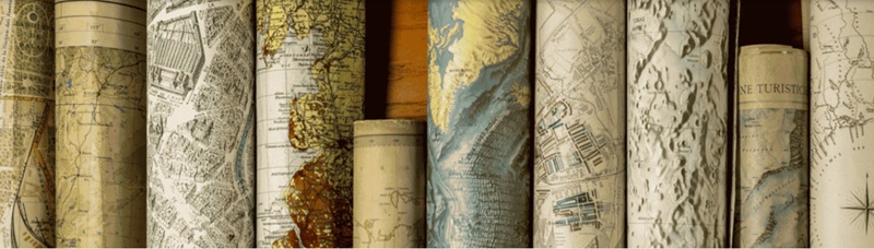 View of a number of rolled-up maps, arranged neatly in a row.