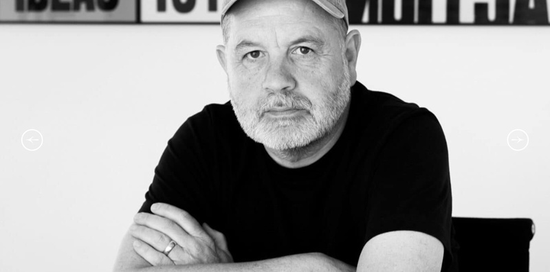 Black & white head and shoulders shot of Anthony Burrill (seated).