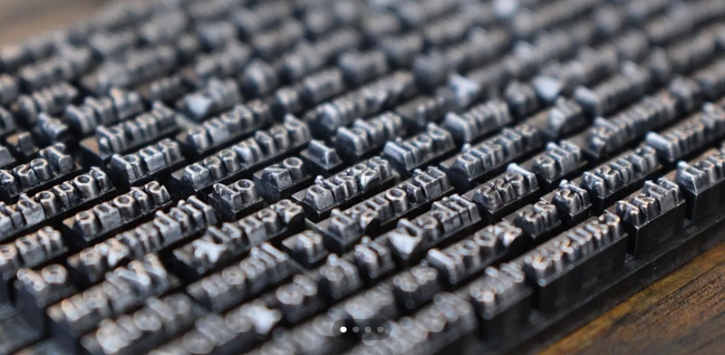 Close‑up view of metal movable type blocks arranged in rows, showing raised reversed letters used in traditional printing.