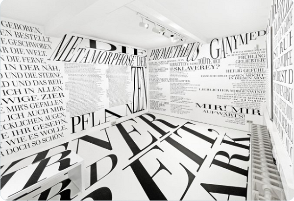 A room with the walls and floor covered with different typography (in black print against a white background)