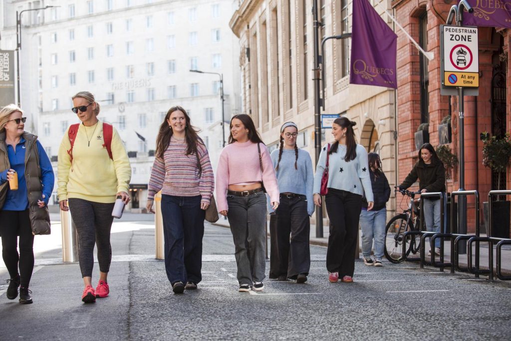 Group of young women walking along a cobbled road on a bright day