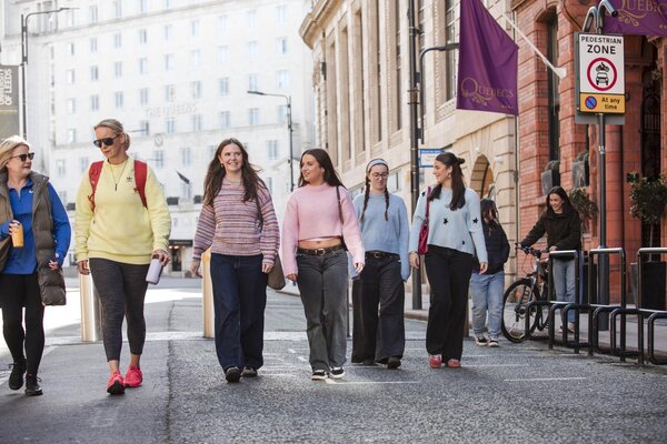 Group of young women walking along a cobbled road on a bright day